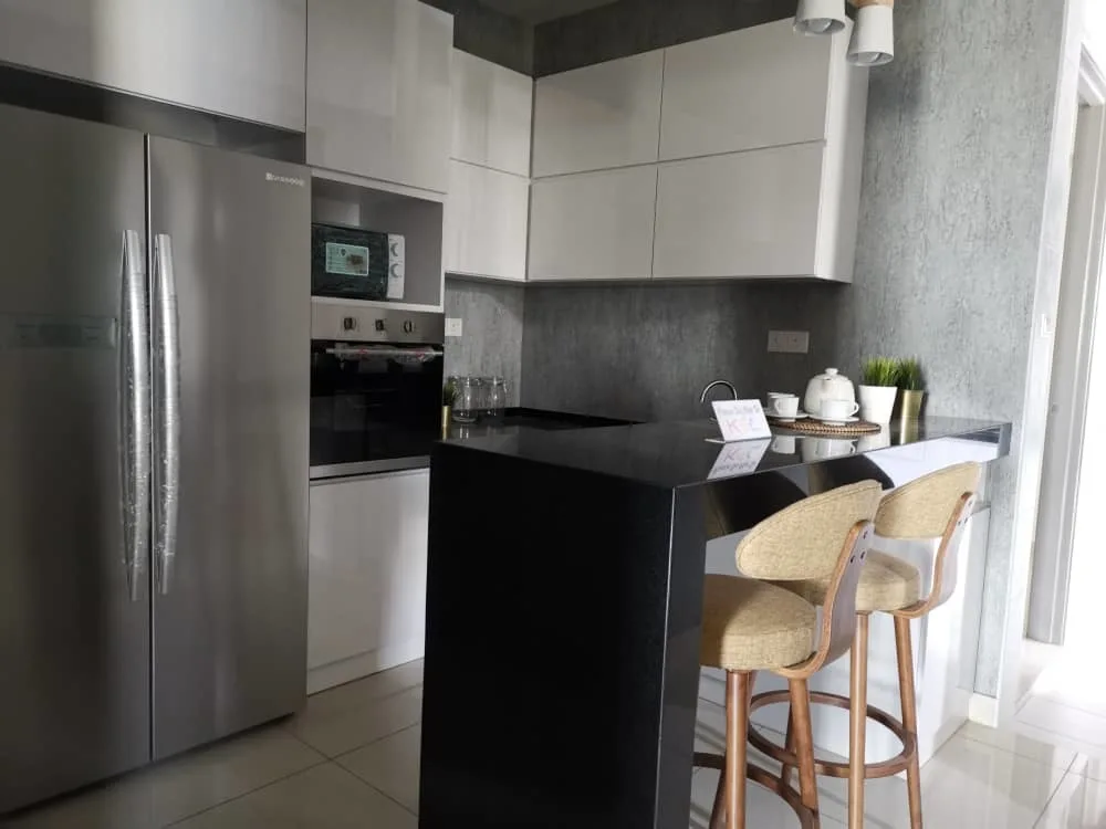 KSL Mutiara Bestari Taman Nusa Bestari Image shows a kitchen interior with a refrigerator, oven, microwave, cabinets, and a breakfast bar with two stools. in Skudai, Freehold property development, photo